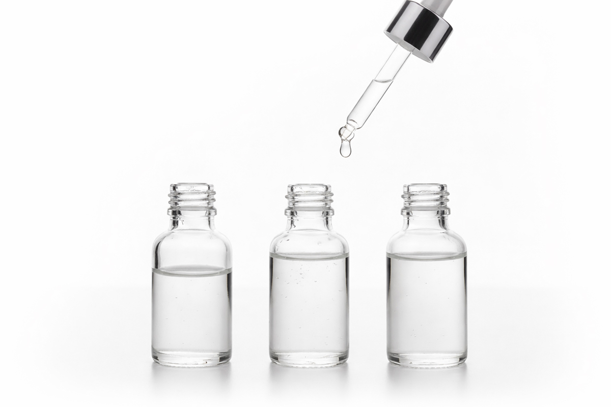 3本並んだ小瓶の中にはそれぞれ違う量の液体が入っている。小瓶の上にはスポイトがあり、先端から液体が落ちかけているところ。
